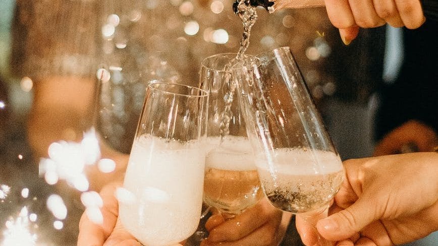 person pouring champagne on champagne flutes